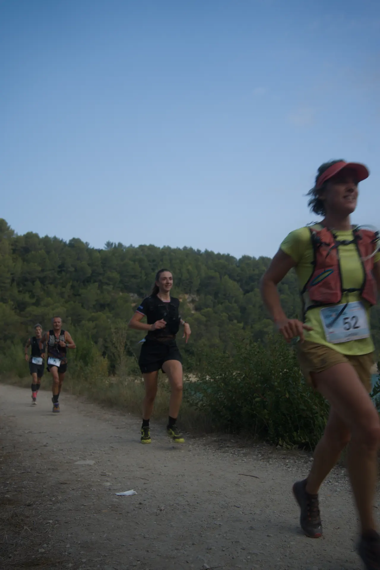 Une coureuse en casquette rouge et gilet d’hydratation, vue de près.