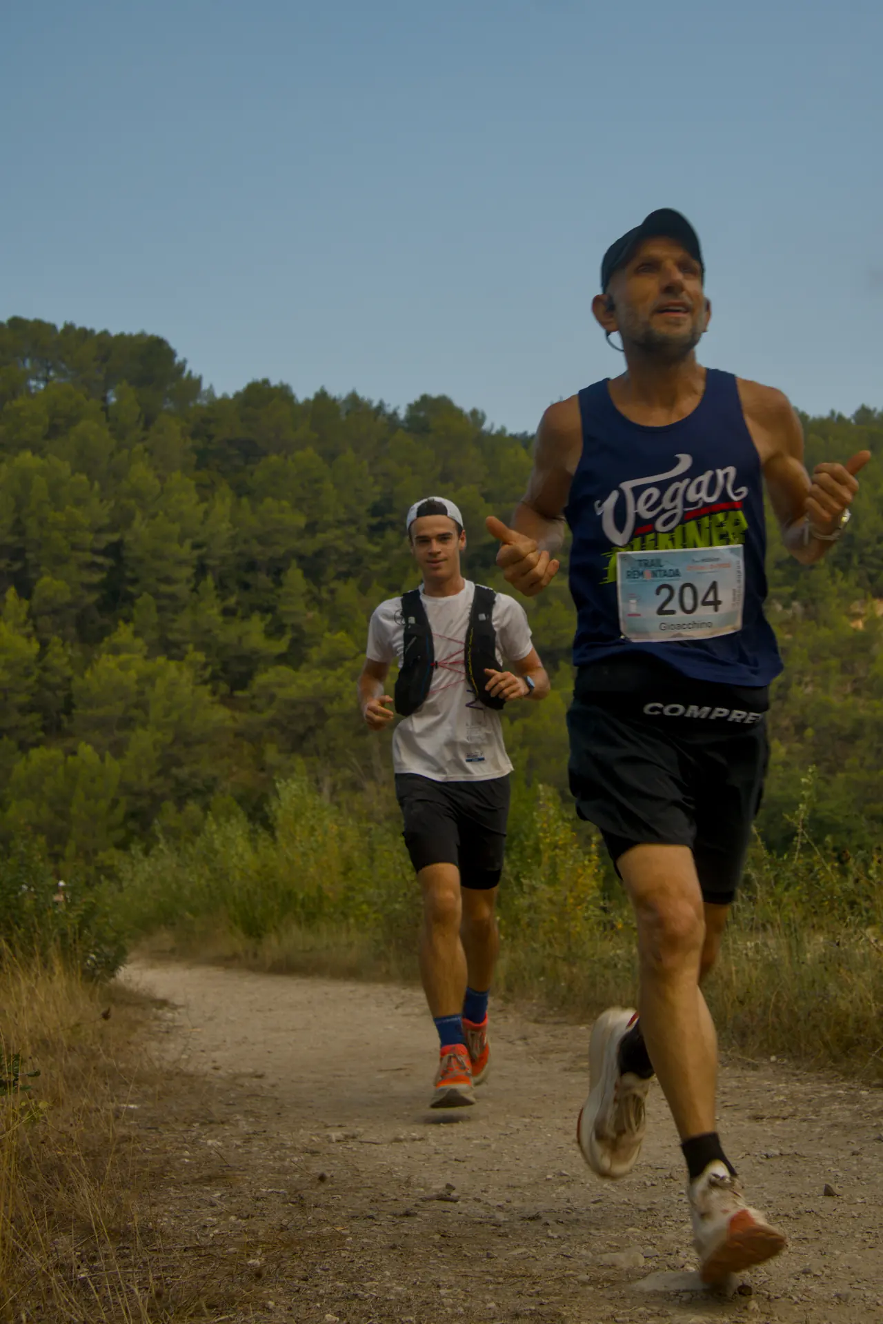 Un coureur en débardeur lève les deux pouces en passant devant l’objectif.