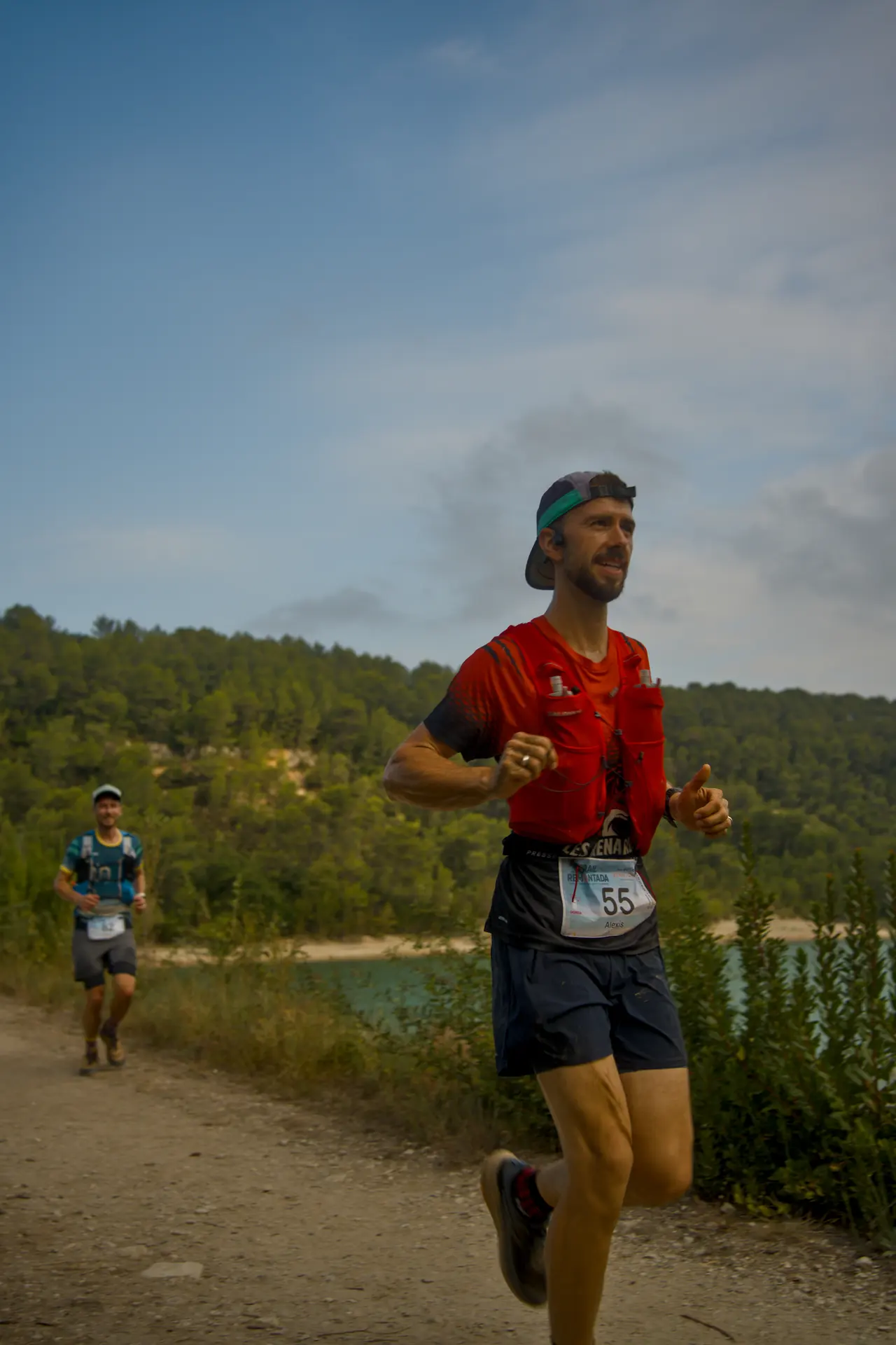 Un coureur en tee-shirt rouge, casquette à l’envers, regarde au loin.