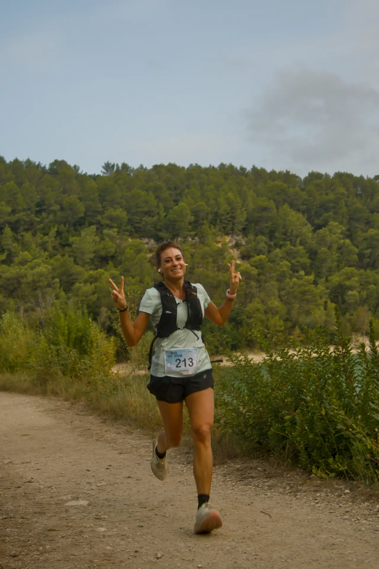 Une coureuse fait le V de la victoire des deux mains en pleine course.