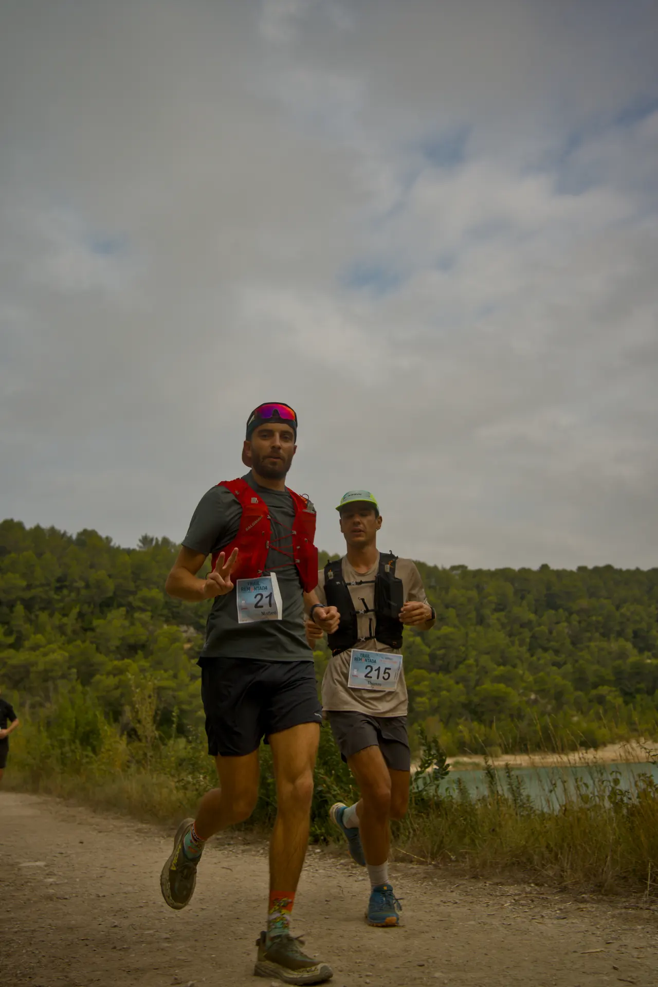 Deux coureurs côte à côte, l’un salue l’objectif.