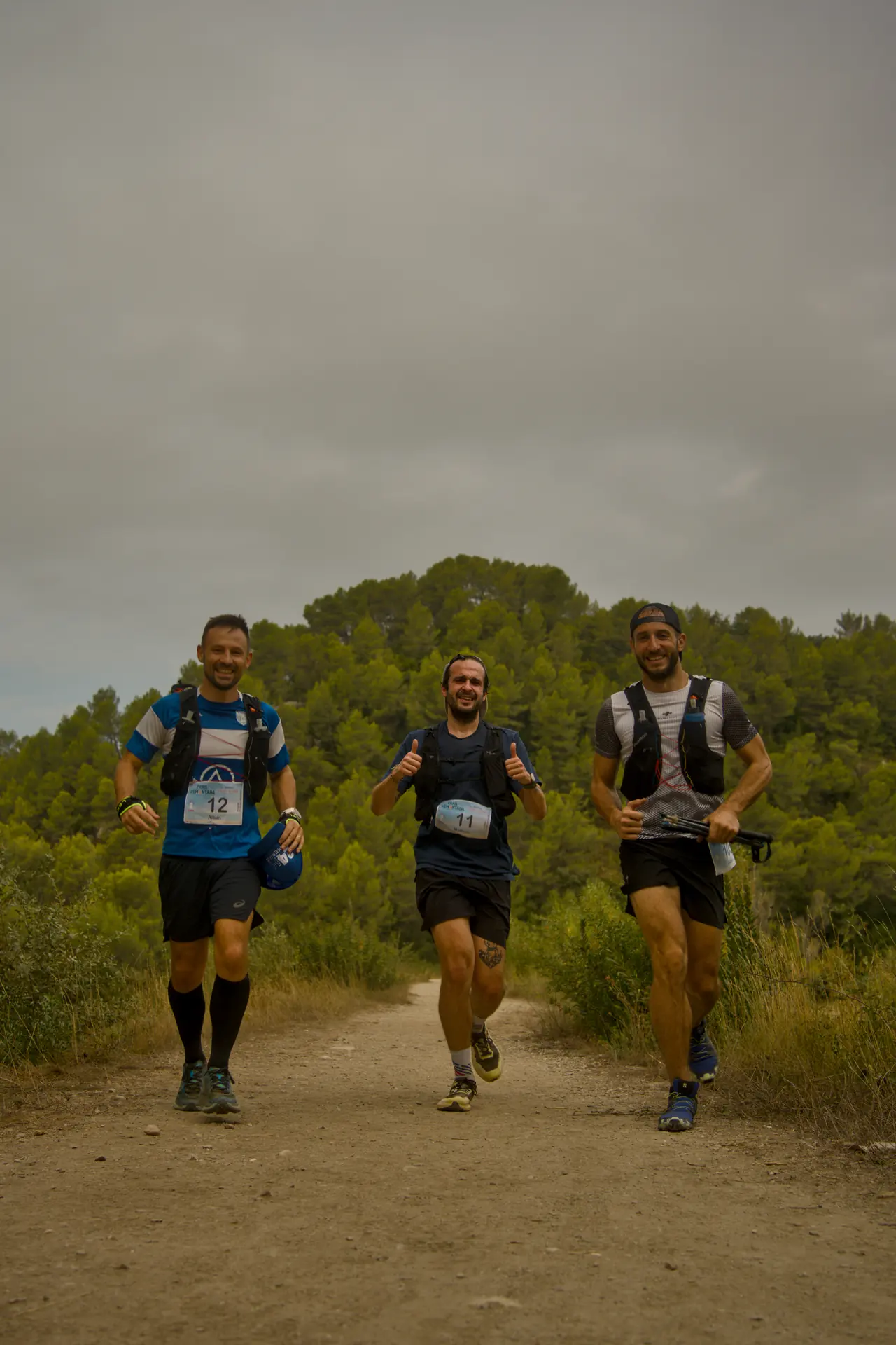 Trois coureurs avancent de front sur un sentier, tout sourire.