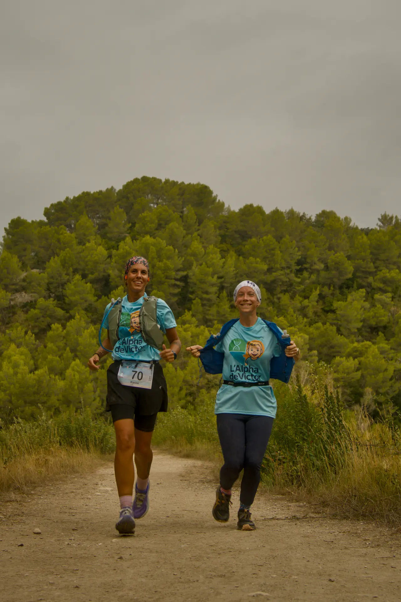Deux coureuses côte à côte sur un sentier, grand sourire.